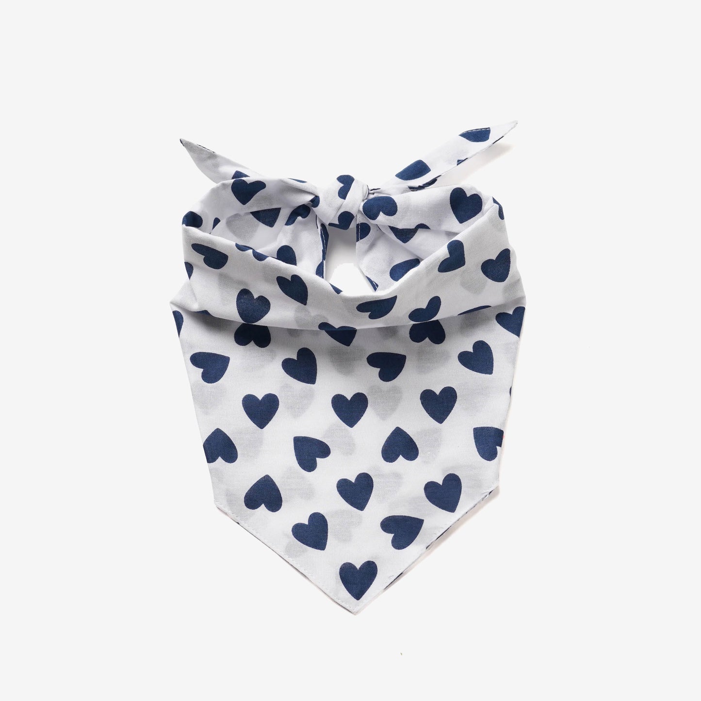 White bandana with navy blue heart patterns, tied at the top, displaying a playful and stylish accessory for pets or fashion.