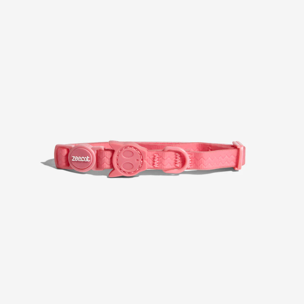 Pink cat collar with an adjustable buckle, featuring a cute cat face design and the brand name "zee.cat" on it.
