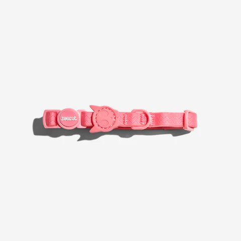 A soft pink pet collar featuring a circular buckle and the brand name "zee cat" embossed on it.