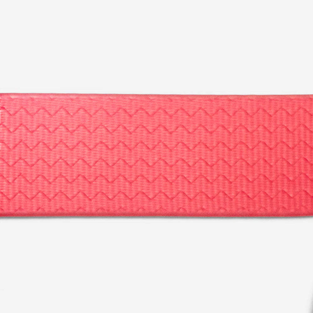 A textured coral pink cat collar with a zigzag pattern, laid flat against a white background.