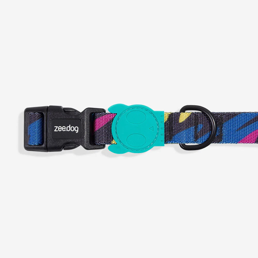 A colorful dog collar featuring a black buckle, vibrant patterns in blue, pink, and yellow, and a teal logo tag.