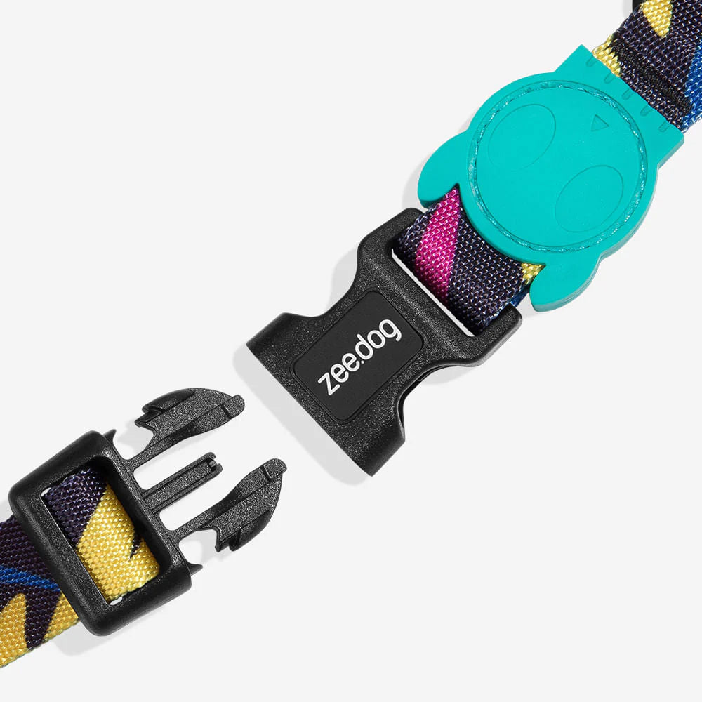 Colorful pet collar buckle with a teal cartoon character and "zeed:dog" logo, displayed on a patterned strap.