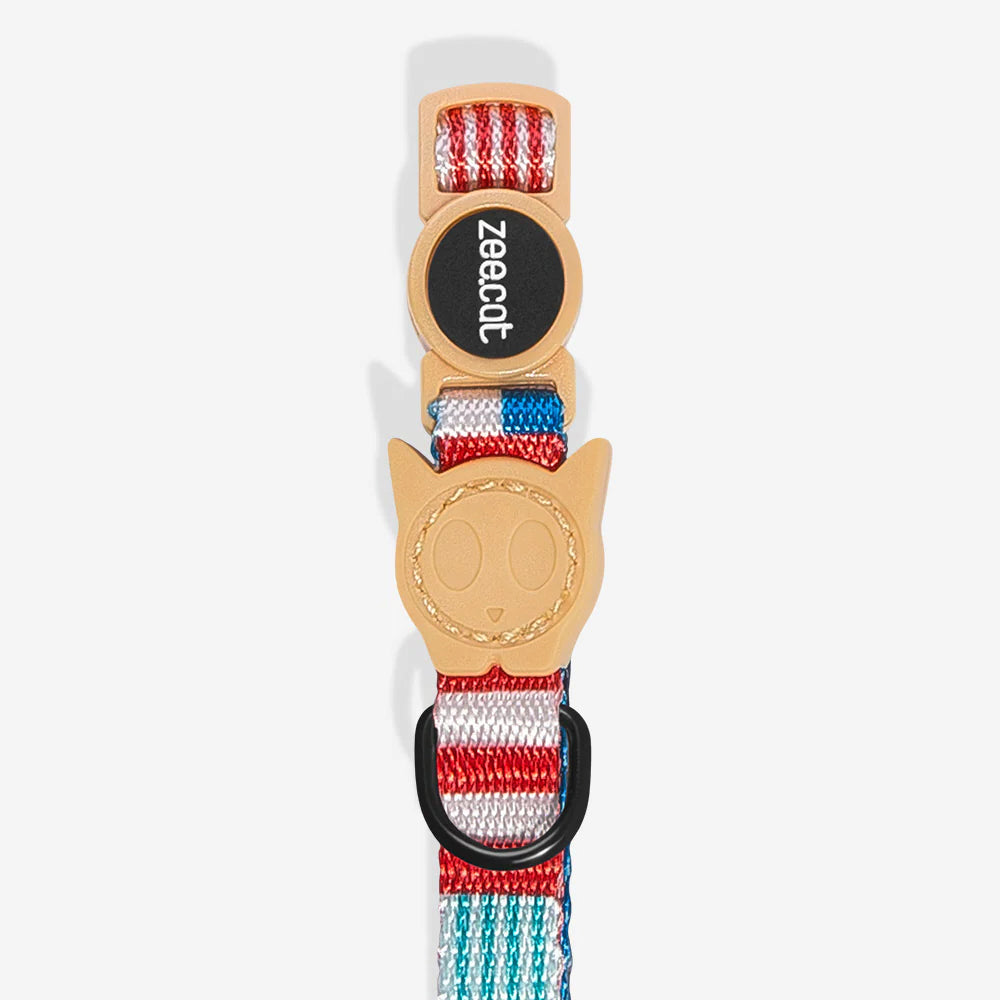 A colourful pet collar featuring a cat-shaped charm and the brand name "zee cat" on a striped strap of red, white, and blue colours.