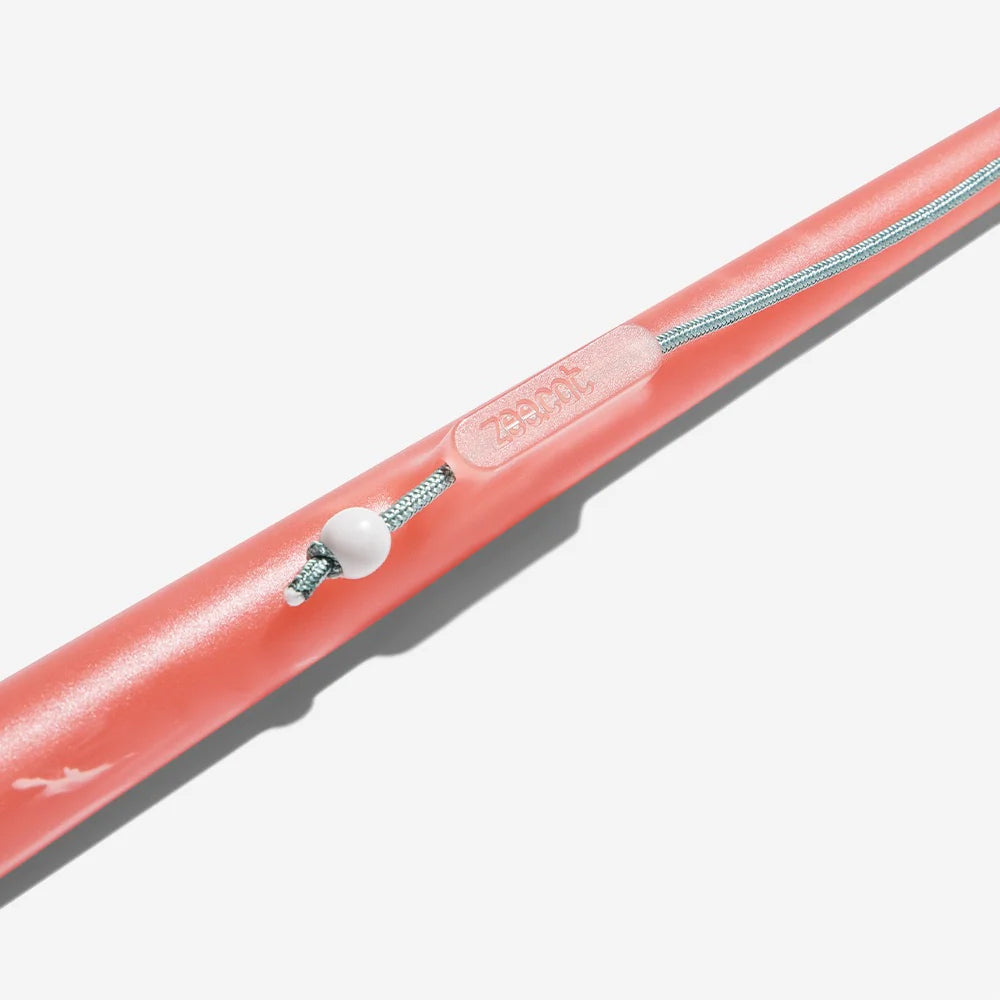 Close-up of a pink Zeecat wand, featuring a textured grip and a white bead for adjusting a silver cord.