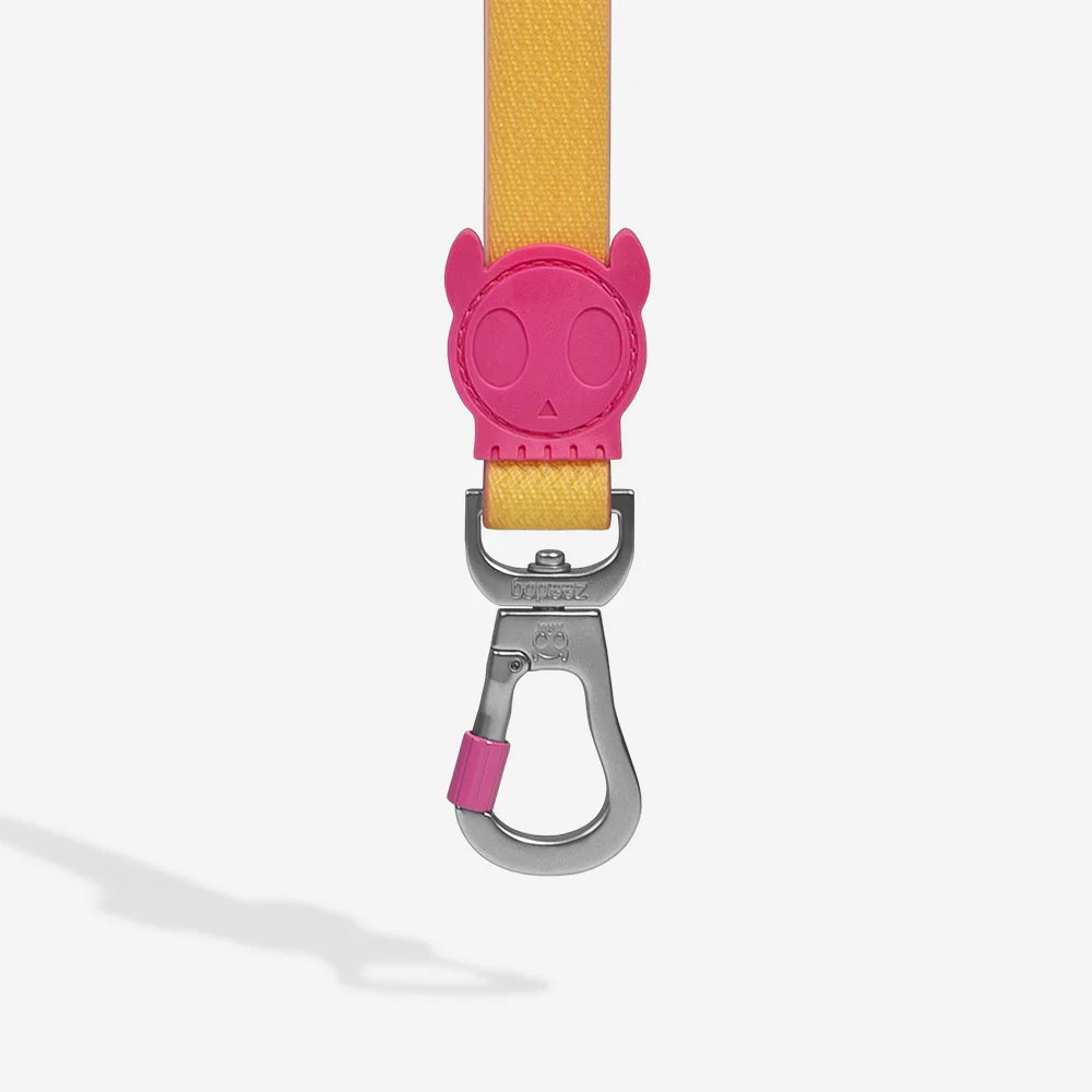 A vibrant yellow pet leash featuring a pink skull-shaped clasp attachment for added style and security.
