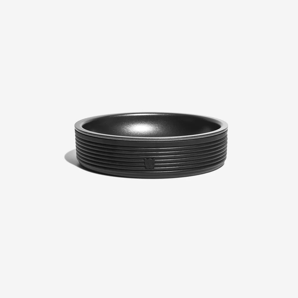 A sleek, black, round bowl with subtle ribbing and a small logo, ideal for modern home decor or serving.