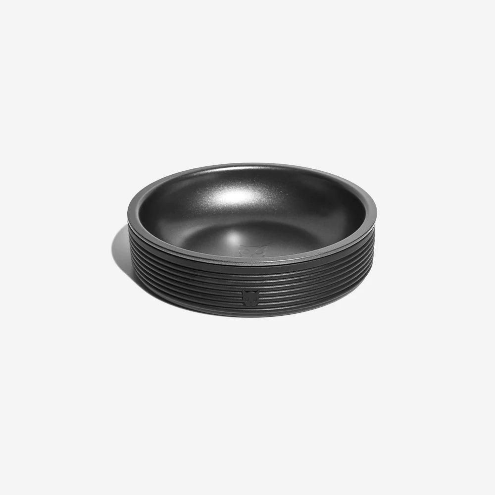 A sleek, round black bowl with subtle ribbing around the edge, designed for modern pets.
