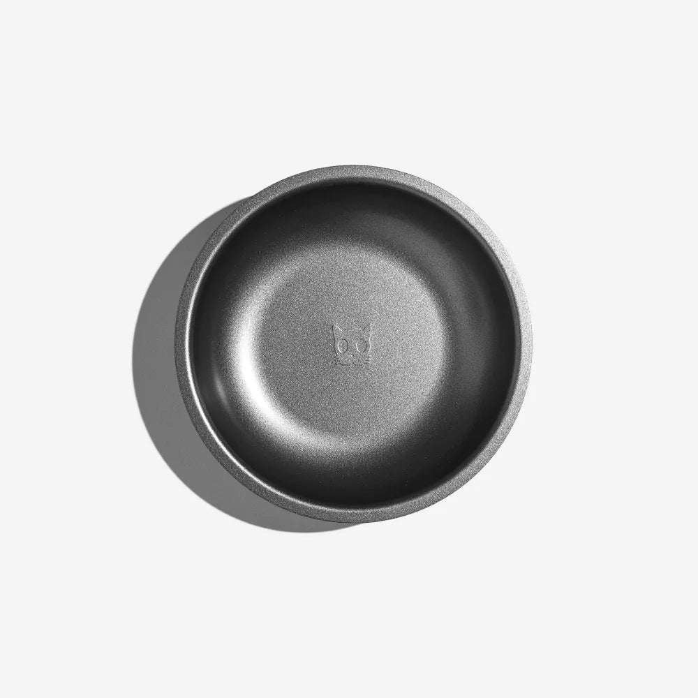 A sleek, round, matte gray bowl with a subtle embossed design of a cat face at the bottom, casting a soft shadow.
