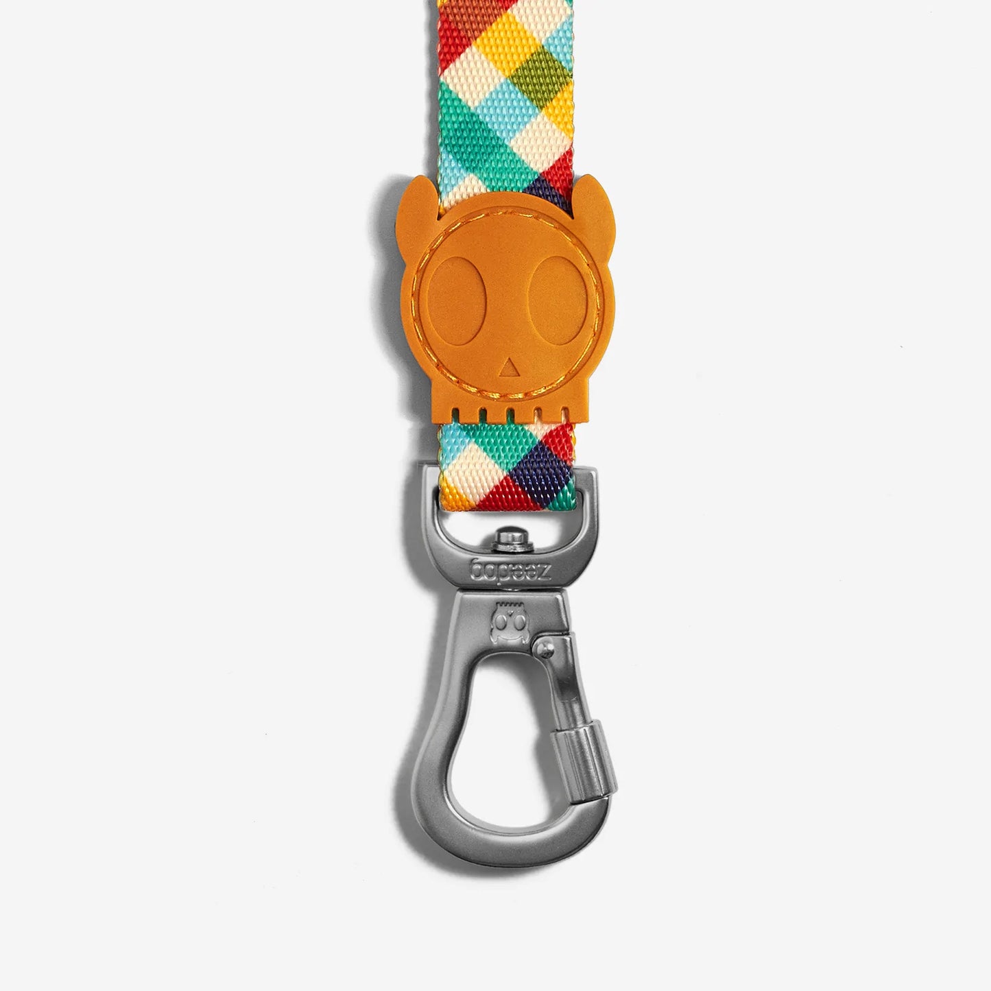 Colourful plaid strap with a playful skull-shaped leather tag and a silver carabiner clip, designed for fun and functionality.