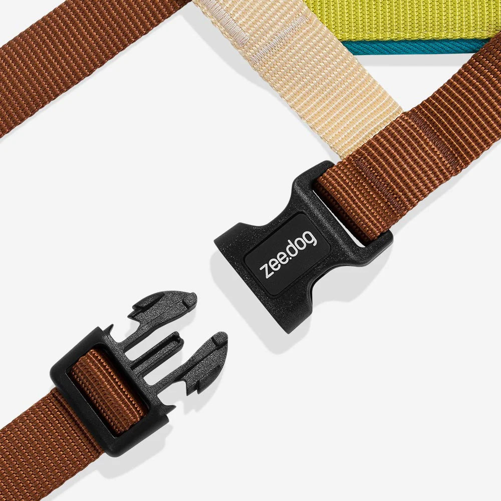 Unbuckled dog harness black clip with brown, beige, and green straps on a white background.