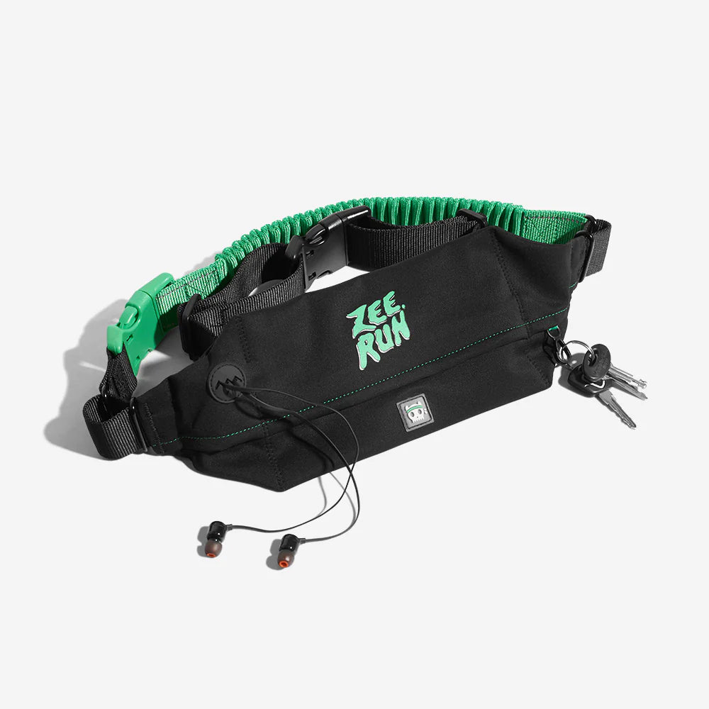 Black running waist pack with green accents, earphones, and keys on a white background.