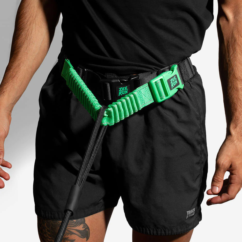 Man in black shorts with green adjustable running belt and cable attached.