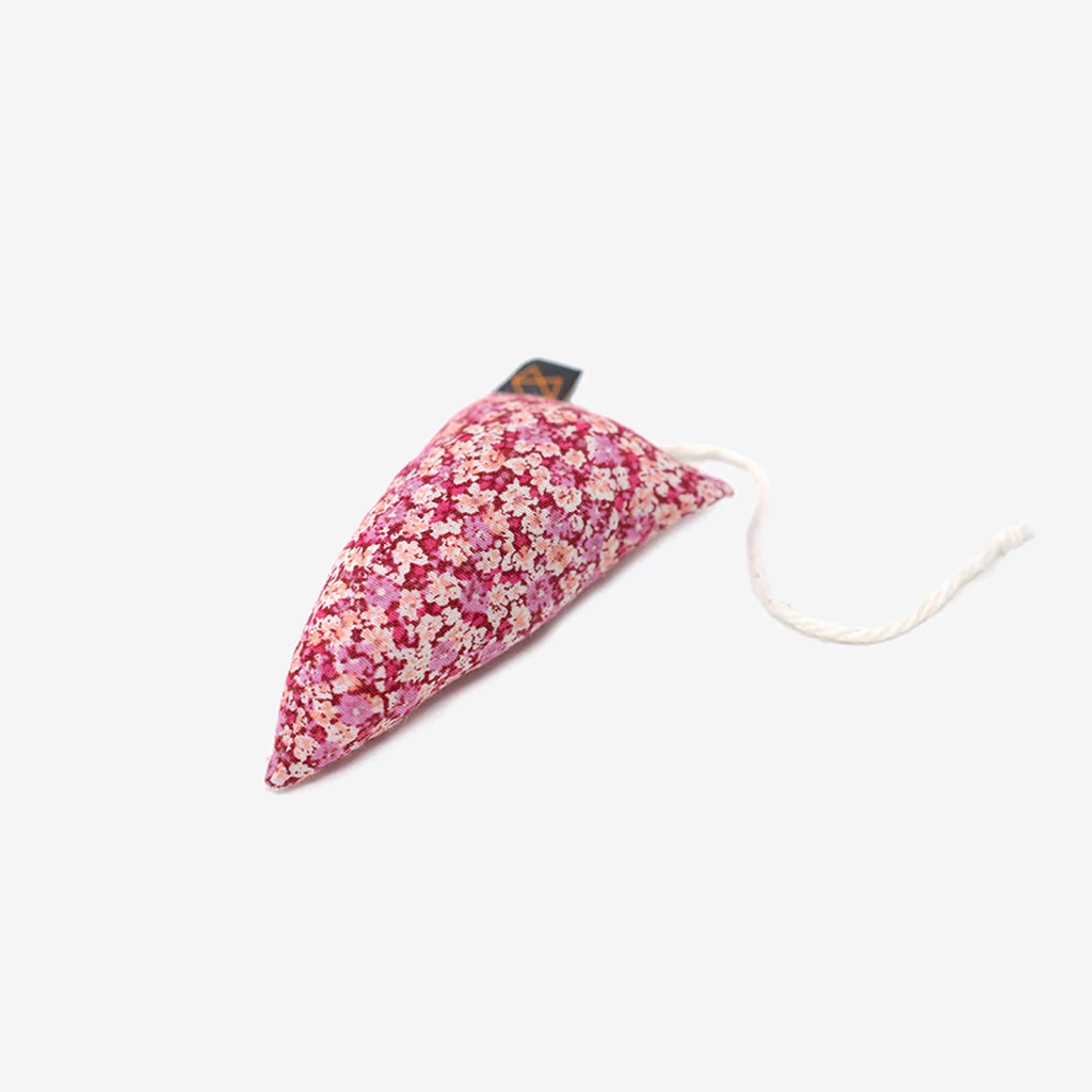 A small, pink floral fabric weight with a rope attached, designed for sewing or crafting projects.