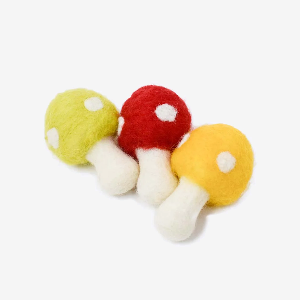 Three colorful felt mushrooms in green, red, and yellow, each with white polka dots on top and a beige stem, arranged closely together.