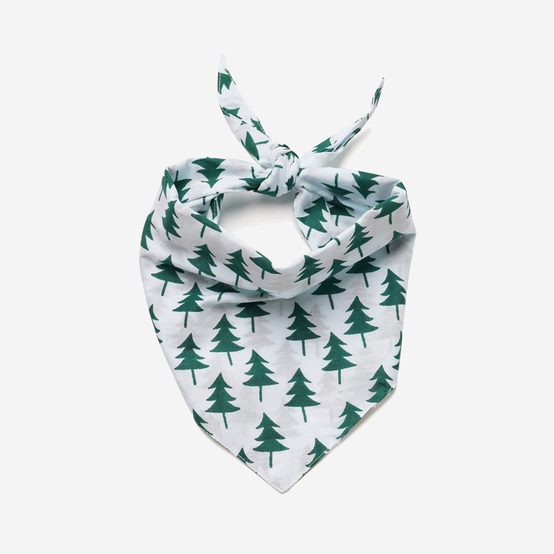 A white dog bandana with a nature-inspired design featuring green Christmas trees printed on it.