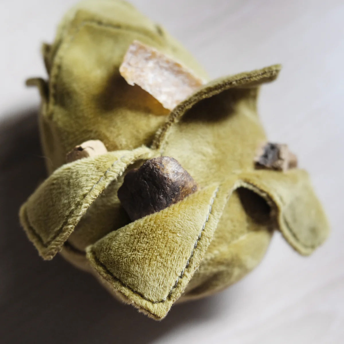 A plush green artichoke dog snuffle toy, with air feezed dried dog treats inside the small leafy pockets.