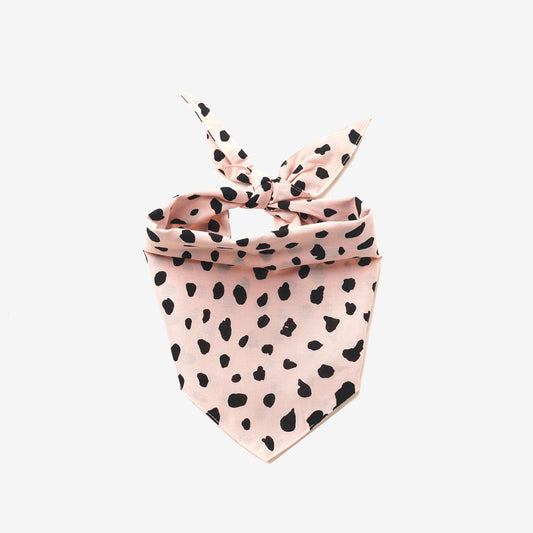 A 100% cotton dog bandana patterned with black leopard spots on pale pink