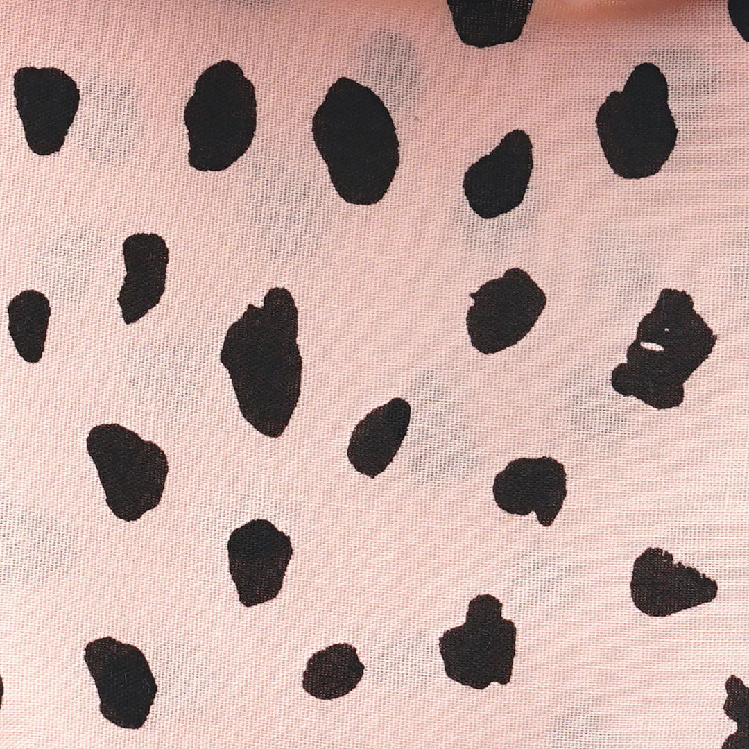 Close up fabric of a 100% cotton dog bandana with black leopard spots on pale pink