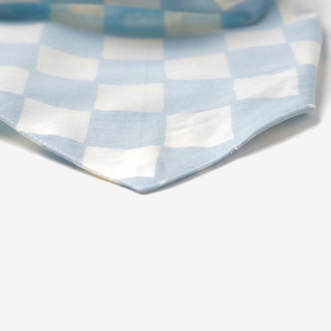 a close up of a 100% cotton dog bandana with a checkered pattern in pale blue and white