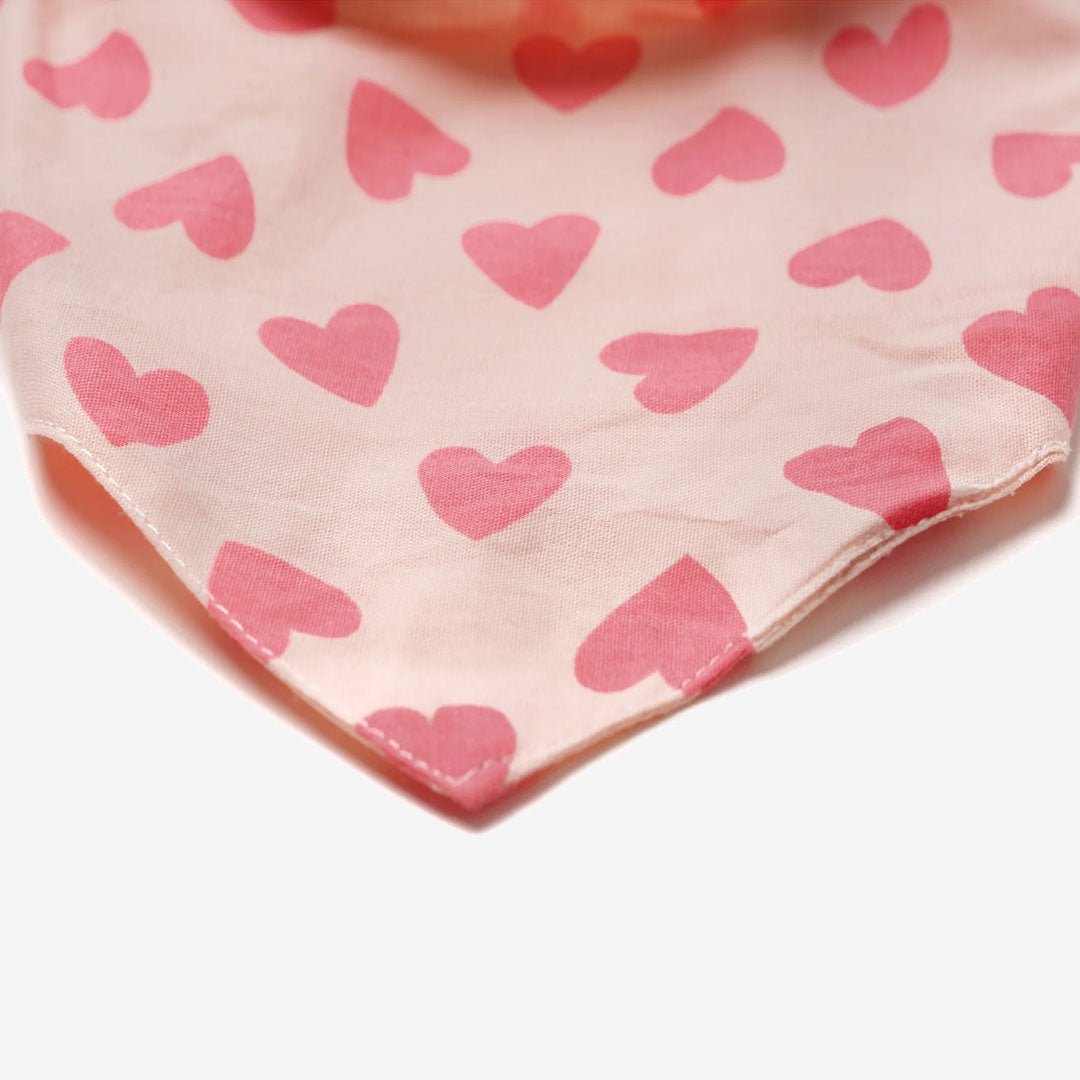 Close up fabric of a 100% cotton dog bandana patterned with rose pink hearts on pale pink