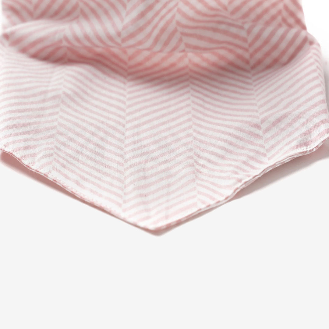 Close up fabric of a 100% cotton dog bandana patterned with pale pink herringbone