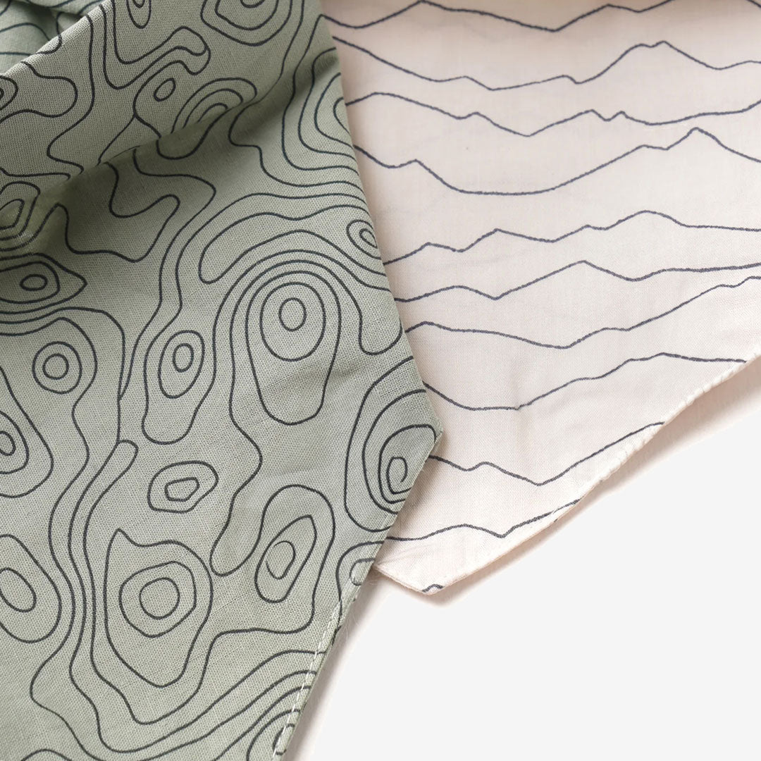 A fabric close up of 100% sage green cotton dog bandana patterned with landscape lines