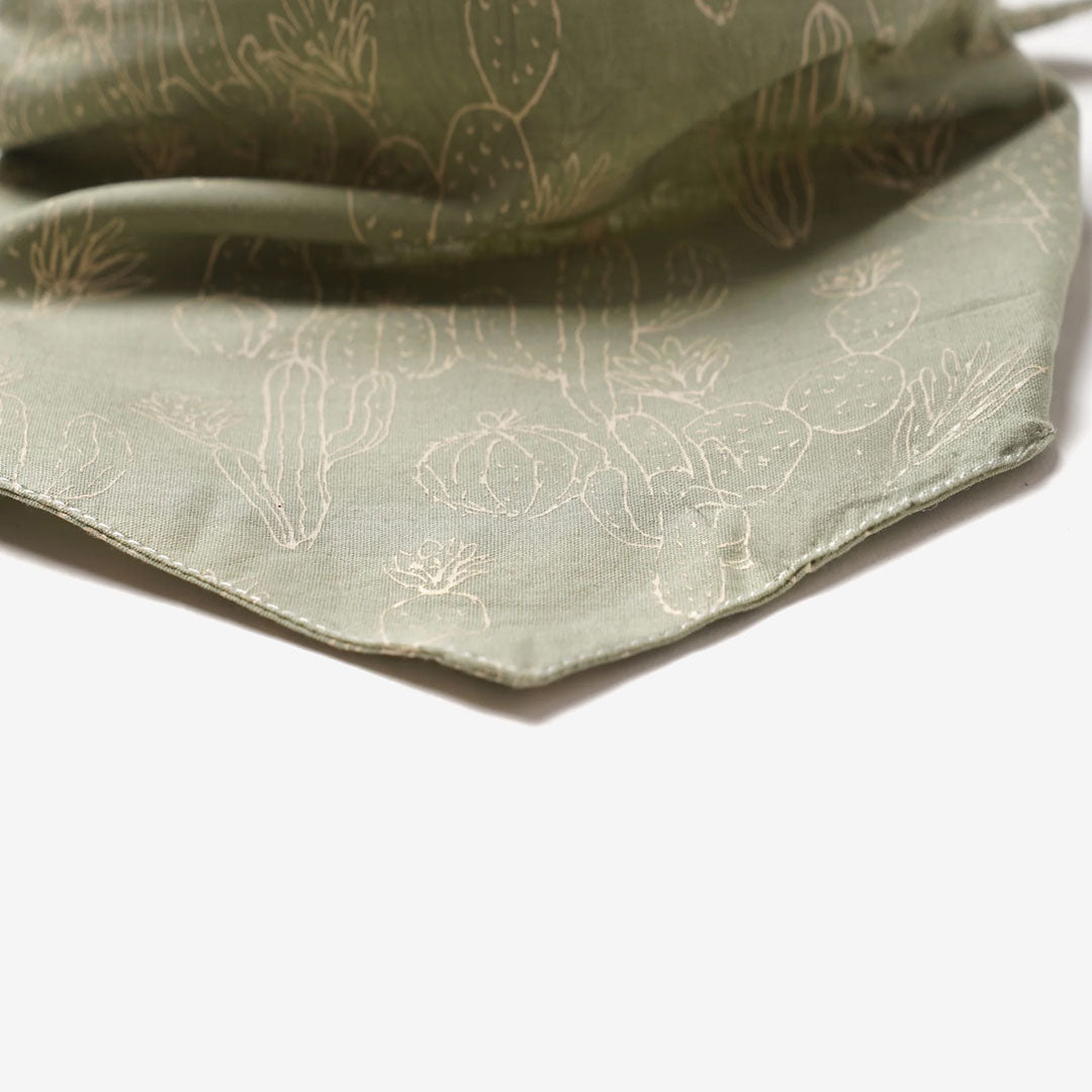 close up fabric of a sage green 100% cotton dog bandana with a cactus pattern