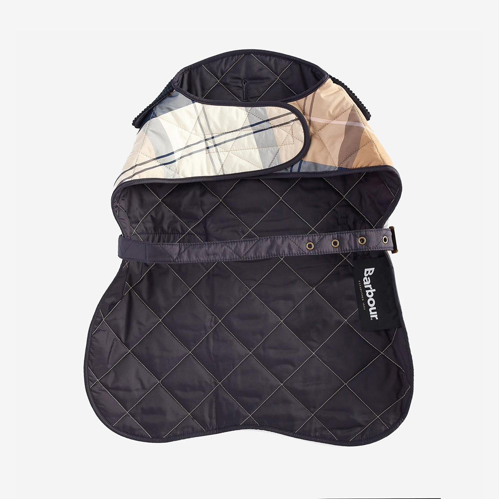 A quilted Barbour dog coat in navy with a patterned beige and blue lining, laid flat on a white background.