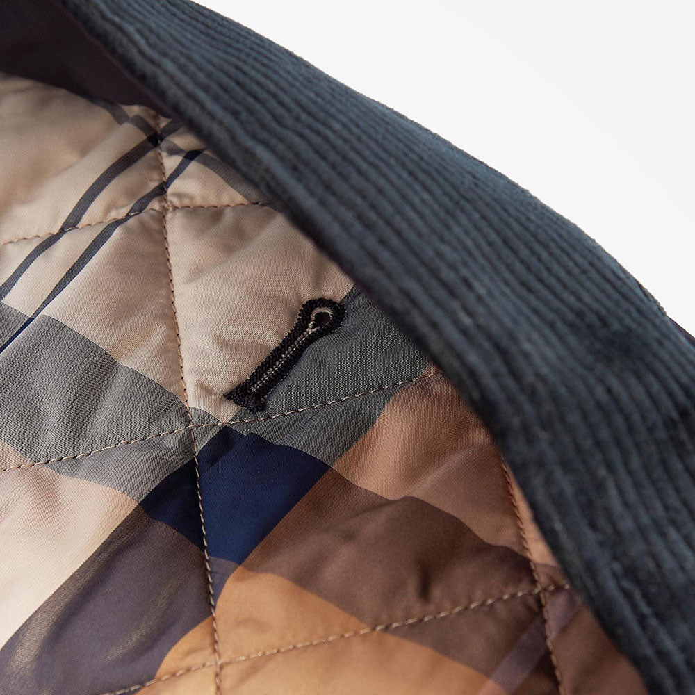 Close-up of a quilted dog jacket interior featuring a patterned lining and a black cord loop detail.