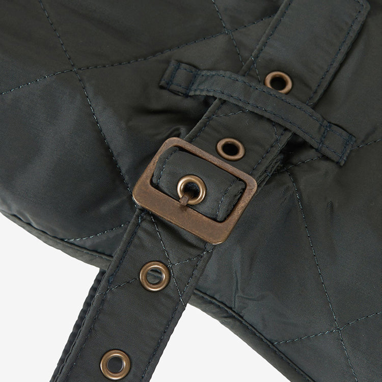 Close-up image of a khaki green quilted jacket with a distinctive metal buckle accent.