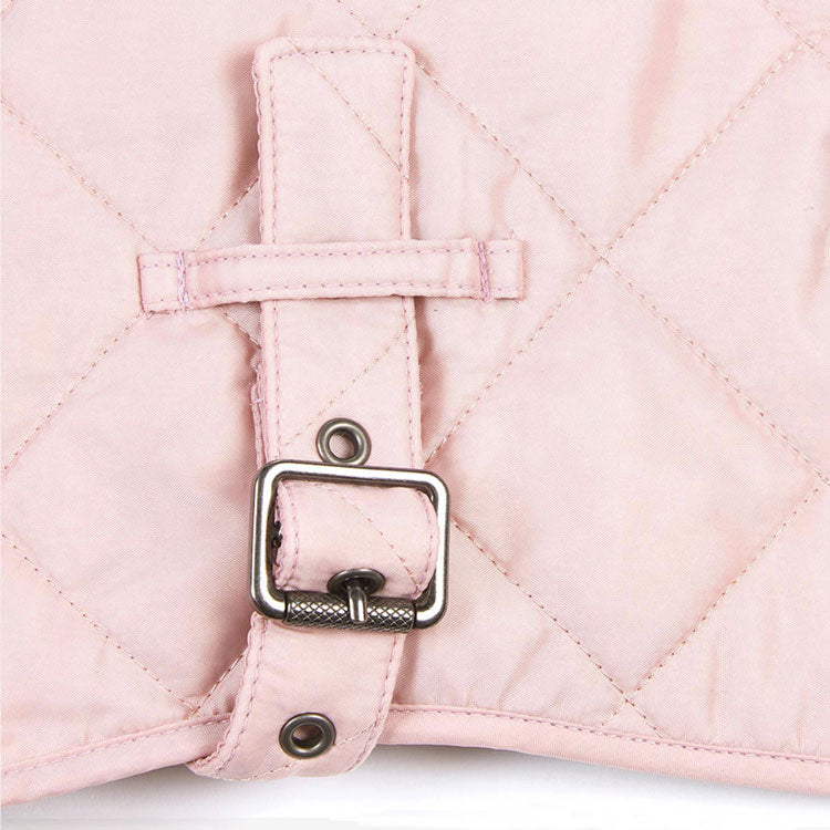 Close-up of a light pink quilted fabric with a metal buckle and loop detail, showcasing stylish fastening design.