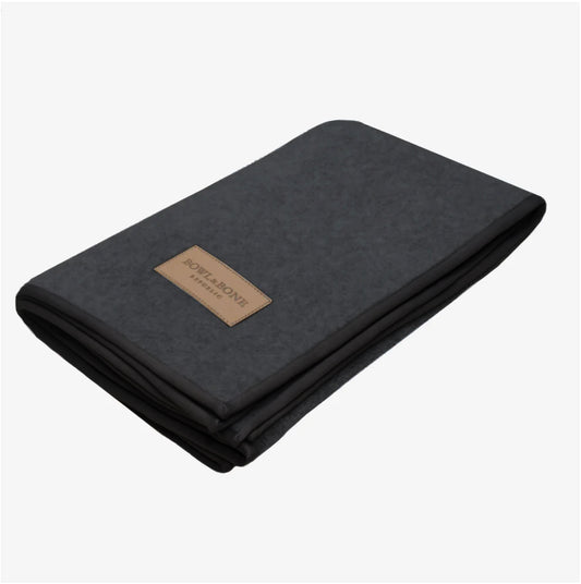 A dark grey plush dog blanket with a leather logo label