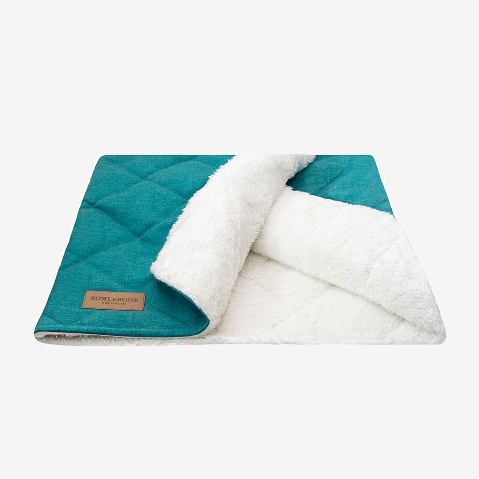 A mint green dog blanket/sleeping bag quilted fully and fully lined with a cream fluffy inner