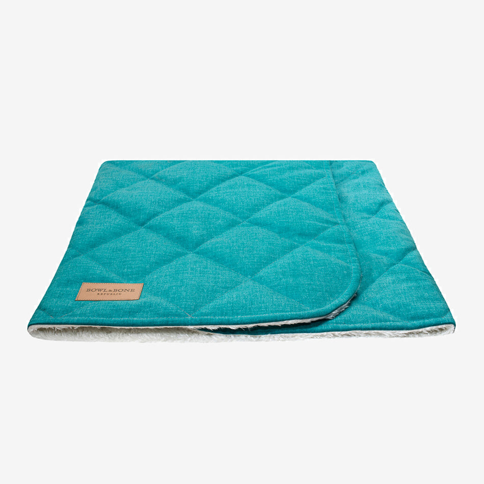 A closed mint green dog blanket/sleeping bag quilted fully and fully lined with a cream fluffy inner