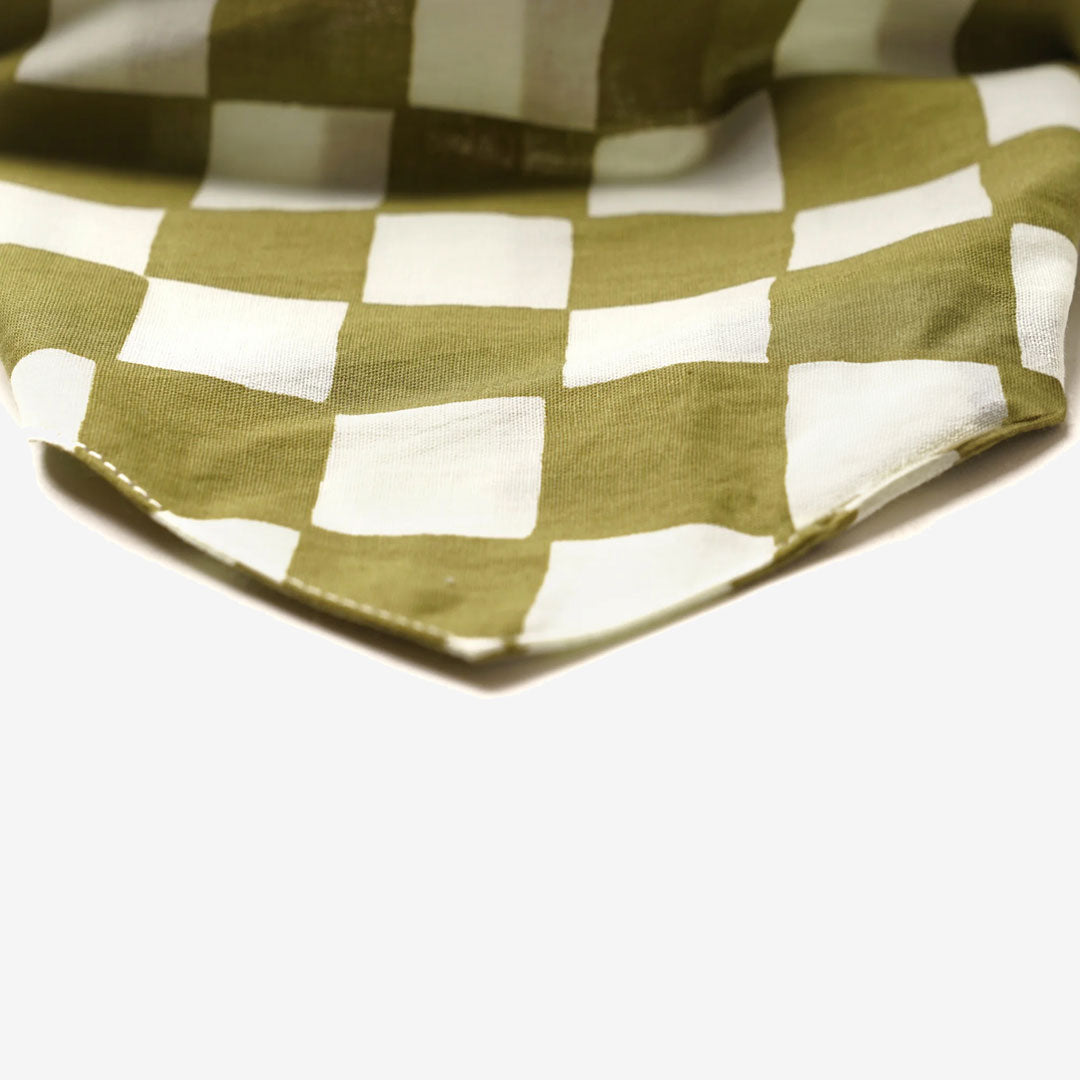 Close up fabric of a 100% cotton dog bandana with a checkered pattern in army green and cream