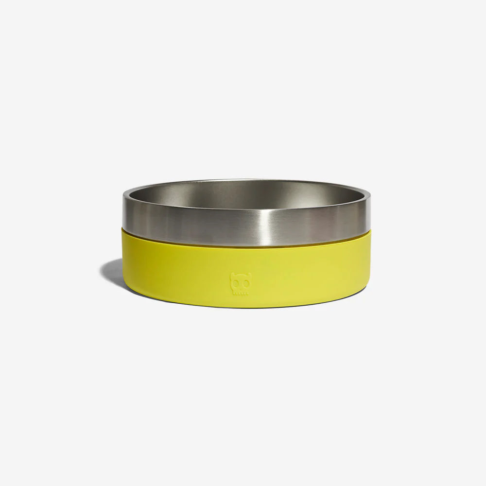 A stainless steel dog bowl with a lime green rubber exterior by Zee Dog resting against a plain white background.