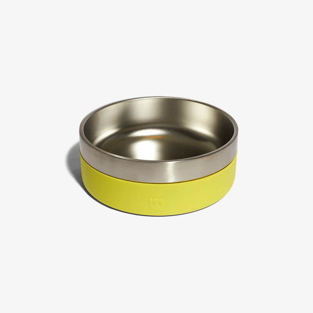 A stainless steel dog bowl with a lime green rubber exterior by Zee Dog resting against a plain white background.