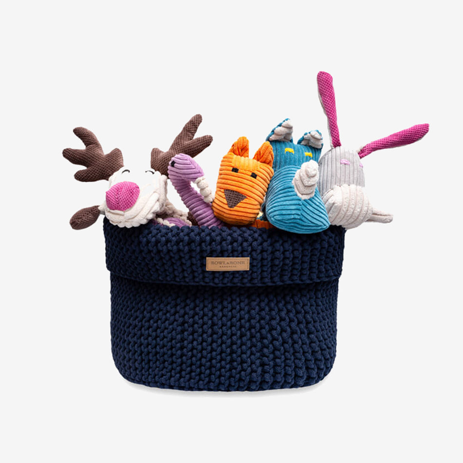 a beige toy basket filled with plush dog toys