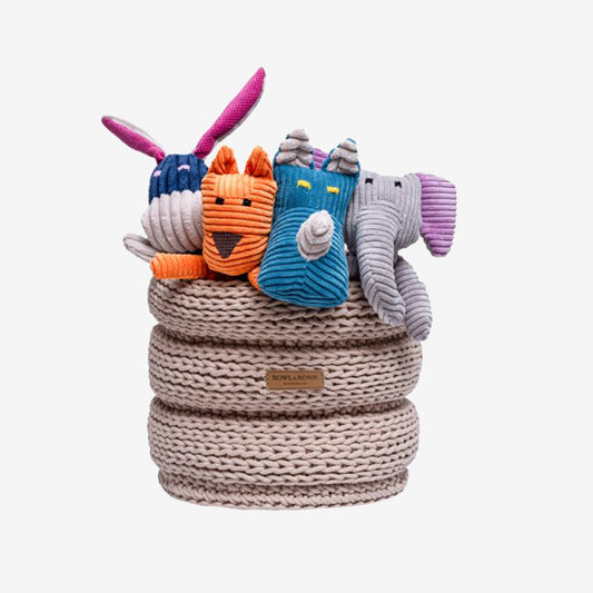 a beige toy basket filled with plush dog toys