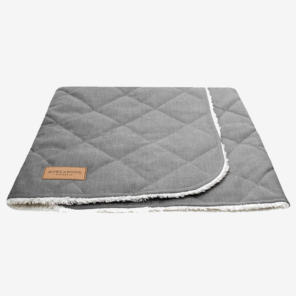 A closed grey dog blanket/sleeping bag quilted fully and fully lined with a cream fluffy inner